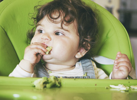 Normal_baby-eating-food-in-her-green-highchair-2021-09-02-12-43-49-utc